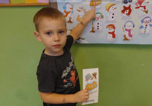 Chłopiec odszukuje na plakacie bałwanka które wskazuje mu zdjęcie