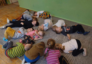 Dzieci leża na dywanie ukazując jak bałwanek się roztapia