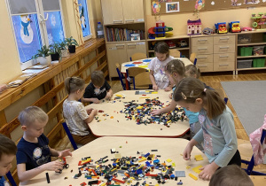 Cała grupa buduje przeróżne konstrukcje z klocków Lego.