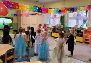 Dzieci z grupy Motylki tańczą i naśladują ruchy do piosenki wyświetlanej na ekranie.