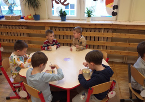 Dzieci zajadają samodzielnie skomponowaną sałatkę owocową.