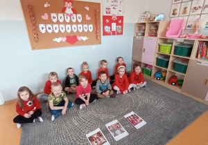 Dzieci siedzą na dywanie i słuchają opowiadania Dzień Przyjaźni w przedszkolu.