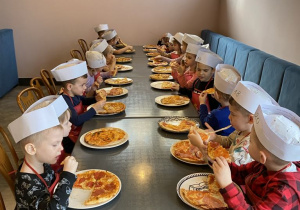 Dzieci zjadają ze smakiem pizze, które samodzielnie przygotowały.