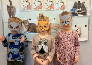 Dzieci pozują do zdjęcia w maskach kotów.