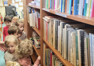 Dzieci szukają książek na półkach.