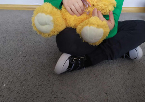Na zdjęciu chłopie przytulający maskotkę Małego Misia.