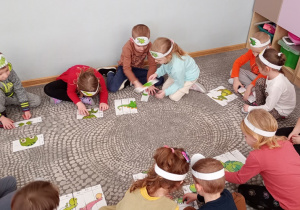 Dzieci układają na czas puzzle przedstawiające dinozaury.