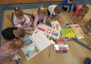 Dzieci z grupy Biedronki oglądają książki z symbolami narodowymi.