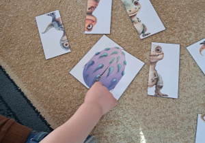 Dziecko układa obrazek przedstawiający jajo dinozaura.