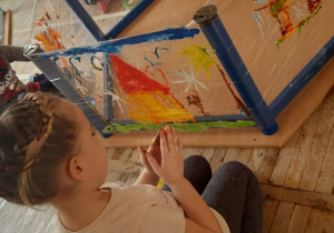 Dziewczynka maluje paluszkami swój obraz.