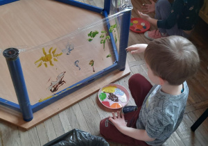 Chłopiec maluje paluszkami swój obraz.