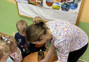 Nauczycielka razem z dziećmi wykonuje eksperyment „Tęcza”.