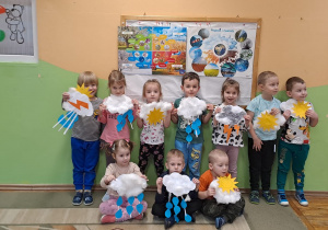 Dzieci pozują do zdjęcia ze swoją pracą plastyczną „Wiosenne chmurki”.