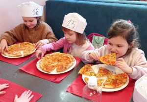 Zdjęcie przedstawia trzy dziewczynki jedzące pizzę.