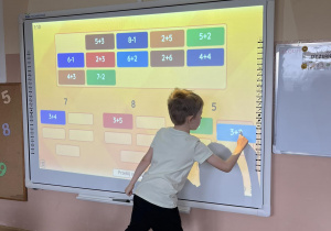 Chłopiec rozwiązuje równanie na tablicy multimedialnej.