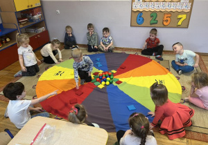 Dzieci segregują kolorowe woreczki i piłeczki według koloru.