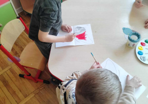 Chłopiec maluje skrzydła motyla.