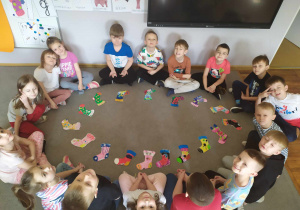 Dzieci prezentują swoje prace plastyczne – ozdobione na kolorowo skarpetki.