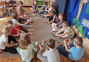 Dzieci siedzą na dywanie i ścigają się, kto pierwszy założy skarpetki.
