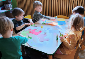 Dzieci przy stoliku wykonuja prace plastyczną