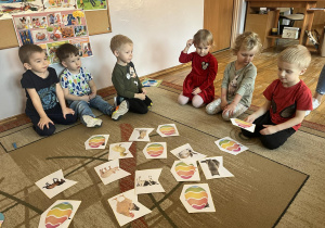 Dzieci siedzą na dywanie, dopasowują pisankę z ukrytym zwierzątkiem do odpowiedniego obrazka.