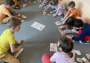 Cała grupa siedzi na dywanie i układa puzzle z motywem marchewek.