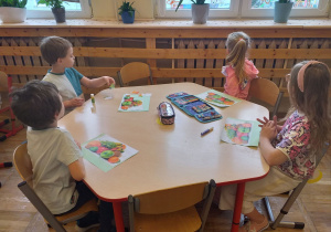 Dzieci z grupy Tropiciele układają z puzzli obrazek przedstawiający owoce.