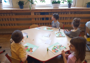 Dzieci układają z puzzli obrazek przedstawiający owoce.