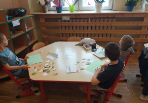 Dzieci układają z puzzli obrazek przedstawiający owoce.