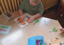Chłopiec koloruje maskę geparda.