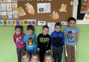 Dzieci z grupy Krasnale stoją na tle dekoracji z marchewkami i napisem Dzień Marchewki