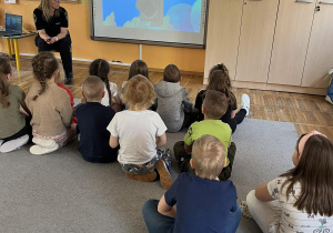 Dzieci oglądają filmik edukacyjny przygotowany przez pracownika Straży miejskiej.