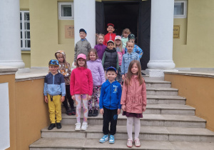 Dzieci z grupy Odkrywcy pozują do zdjęcia na tle budynku Muzeum Regionalnego w Bełchatowie.