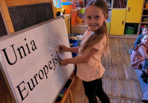 Dziewczynka układa napis z magnetycznych liter Unia Europejska