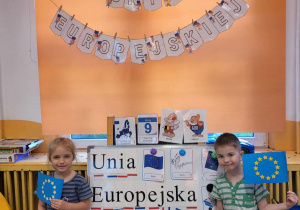 Zdjęcie dzieci na tle gazetki i Unii Europejskiej