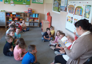 Dzieci z grupy Tropiciele słuchają bajki czytanej przez panią bibliotekarkę.