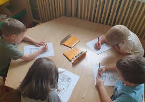 Dzieci z grupy Słoneczka kolorują obrazek przedstawiający Dinka.