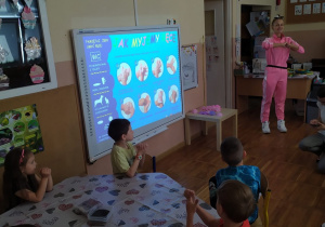 Dzieci z grupy Pszczółki oglądają prezentację na tablicy multimedialnej o historii powstania mydła.