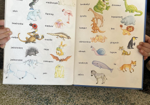 Dziewczynka prezentuje książkę o zwierzętach.