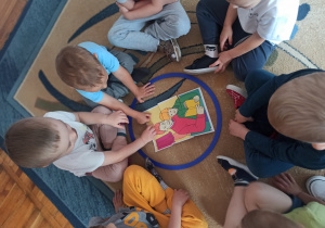 Chłopcy z grupy Biedronki układają puzzle z portretem taty.