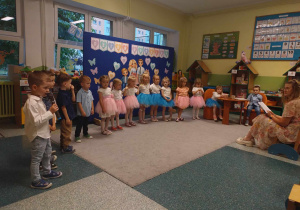 Dzieci ustawione w pół kole na tle dekoracji recytują swoje wiersze