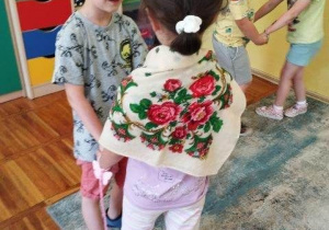 Para dzieci na zdjęciu uczestniczy w zabawie z elementami ludowymi oczywiście z dekoracyjną chustką w kwiaty