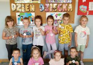 Dzieci z grupy Liski na tle tablicy z napisem Dzień Dziecka pozują z otrzymanymi pamiątkowymi medalami.
