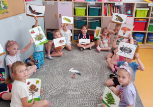 Dzieci siedzą w kole i pokazują obrazki, na których znajdują się smakołyki bocianów i nie.