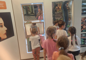 Odkrywcy przeglądają się w lustrach, które zakrzywiają obraz.