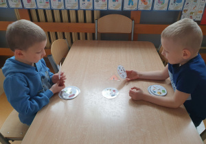 Chłopcy siedzą przy stole, grają w logopedyczne dobble.