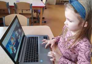 Korzystając z laptopa dziewczynka układa puzzle przy pomocy programu Jigsawplanet.