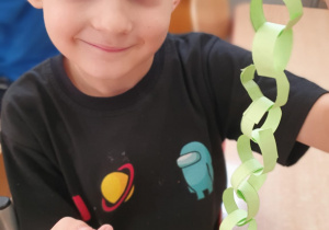 Chłopiec prezentuje własnoręcznie wykonanego węża z papieru.