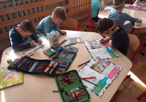 Dzieci z grupy Tropiciele rozwiązują zadania w książeczce projektu "Dzieciaki Mleczaki".