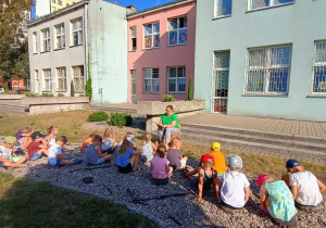 Dzieci siedzą przed nauczycielem i słchają czytanego opowiadania.